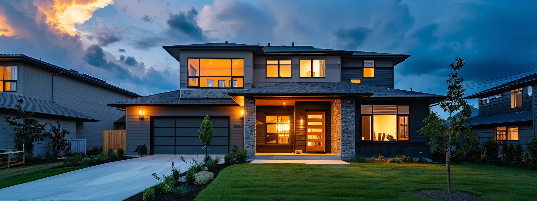 a modern suburban home at dusk, adorned with warm exterior lighting and a neatly maintained lawn, stands resilient against a slightly cloudy sky, symbolizing the importance of reliable backup power for homeowners in the face of impending storms.