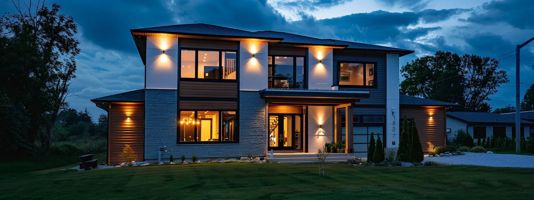 a modern suburban home stands illuminated at dusk, its warm exterior lighting contrasting against a slightly cloudy sky, symbolizing the importance of reliable backup power amidst looming storm clouds.